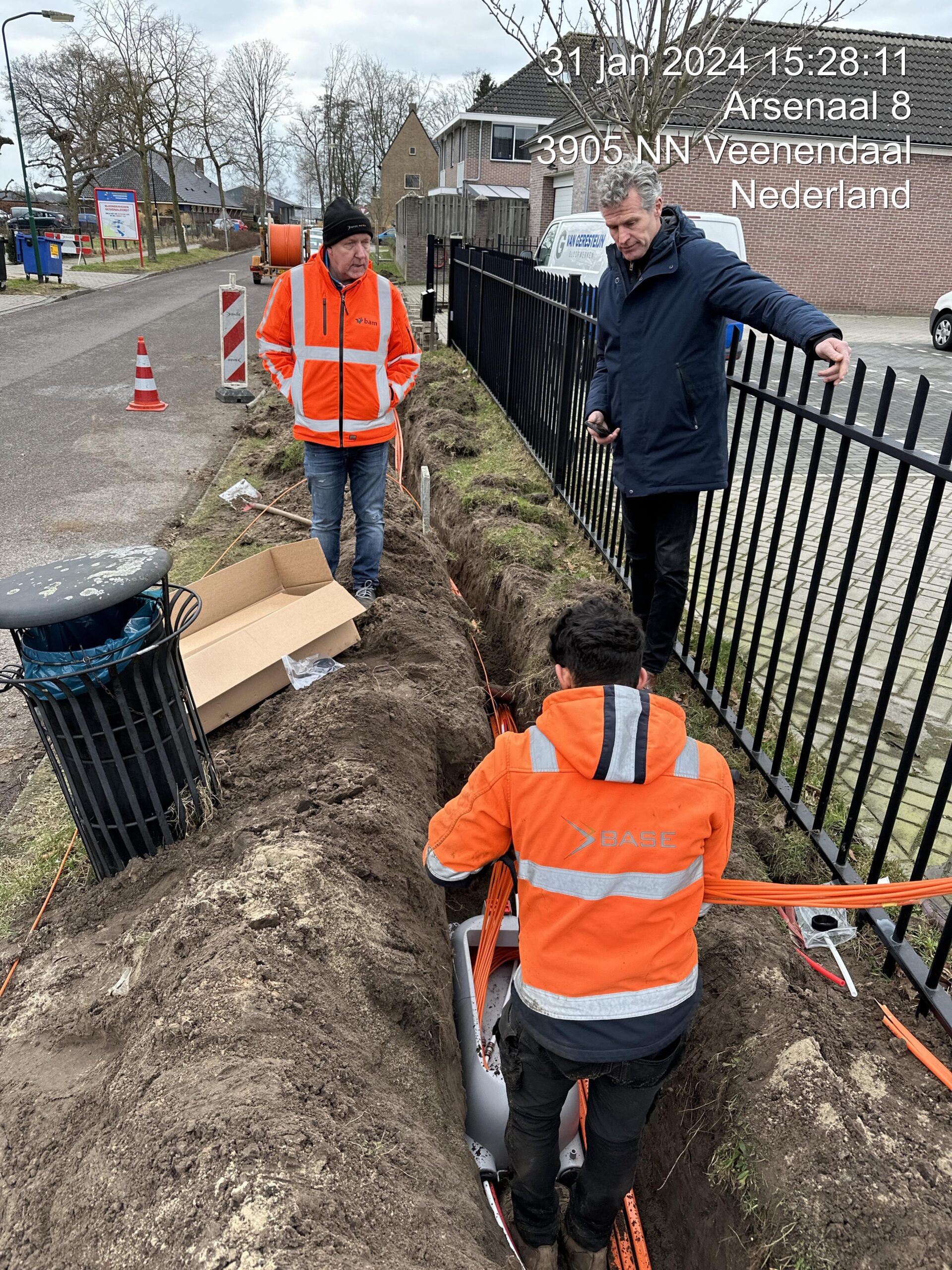 Infrakabels met waarschuwingslint zichtbaar in sleuf tijdens werkzaamheden